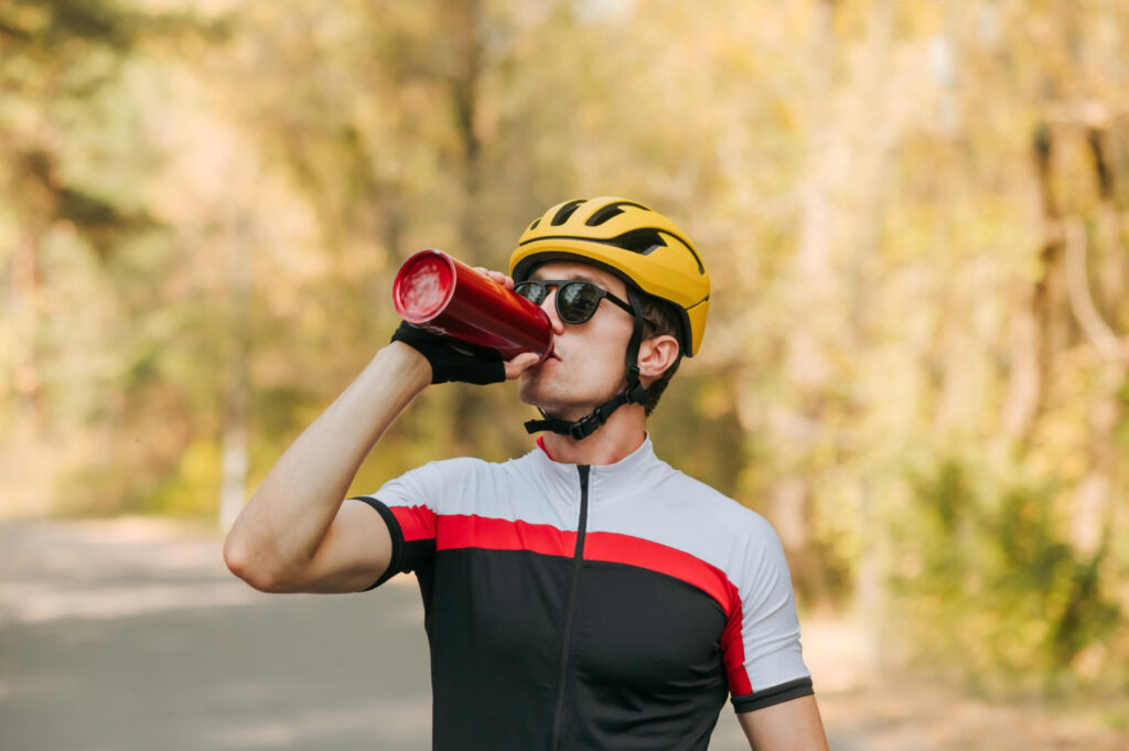 Cycliste prenant un gel énergétique en roulant lors d'une sortie longue